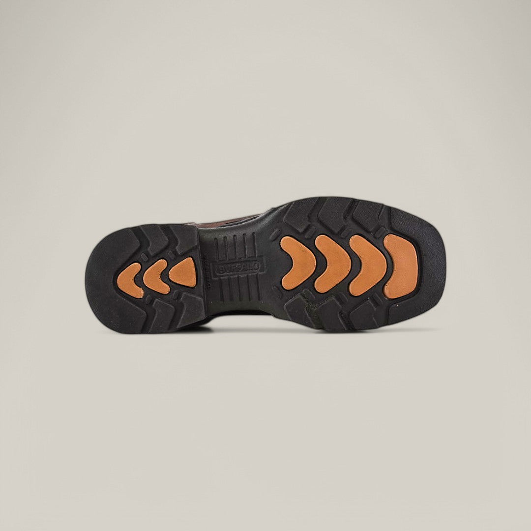 The image displays the underside of the Taurus Honey Composite Toe - E6189 boot, featuring a black outsole with orange chevron-shaped grips. This unique tread pattern enhances traction and durability, while the plain background accentuates the boots robust design.