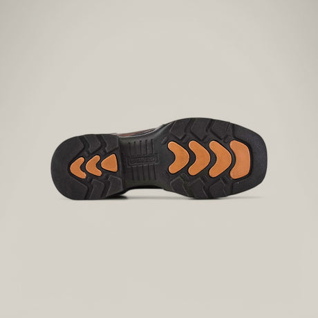 The image displays the sole of the Taurus Moka Soft Toe - E6189 work boot, featuring a black base with orange chevron-patterned rubber traction for durability, set against a plain, light background.