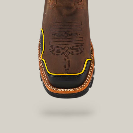 Close-up of the Amazonas Dark Brown Composite Toe - E6256 Work Boot showcasing a square toe, yellow trim, and detailed geometric and curved stitching against a plain gray background.