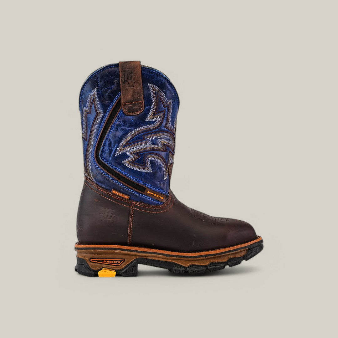 The Amazonas Brown Composite Toe - E6002 is a durable cowboy boot featuring intricate stitching and Texas Country Work Boots flair. It has a waterproof design, rugged sole with visible tread, pull straps, and a decorative blue shaft contrasting with the darker foot.