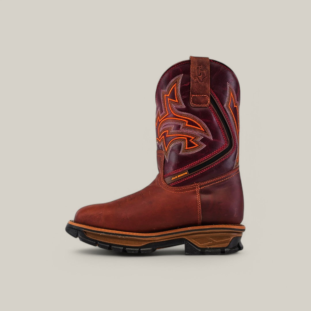 Against a light gray background, the Amazonas Cogñac Composite Toe - E6002 cowboy boot features orange and yellow stitching, a thick rugged sole, and a pull tab for easy wear.