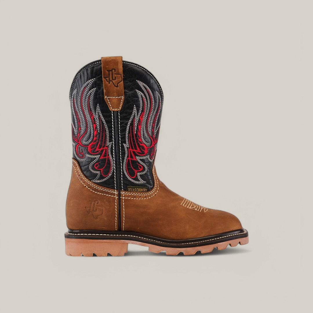 The Crazy Tang Soft Toe - E6015 is a brown leather cowboy boot with a black shaft and red and gray flame embroidery. It features visible white stitching, a tan rubber sole, and a branded emblem at the top, designed for rugged terrain.