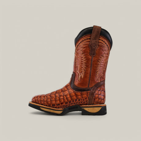 The Alligator Print Cogñac Composite Toe - E6022, a single brown cowboy boot with embossed crocodile pattern and intricate stitching, highlights Texas Country Work Boots durability. It features a black sole and heel with an easy pull loop, set on a plain beige background.