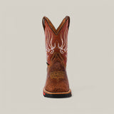 Front view of the Jurasic Honey Soft Toe - E6080 cowboy boot shows a brown hue with intricate white stitching and patterns on the shaft. It features a slightly rounded toe, low heel, rugged texture, and red accent on the soles edge, known for durability.