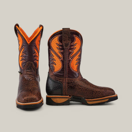 The Jurasic Brown Composite Toe - E6089 boots feature dark brown, textured leather with bright orange flame-like designs. They boast a durable sole and stand out against a plain light gray backdrop.