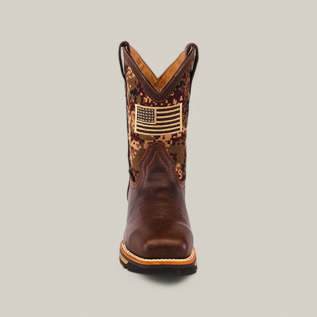 Front view of the Taurus Moka Composite Toe - E6185, featuring a camo pattern and an American flag patch on the shaft. The foot is made from smooth brown leather with durable rugged soles, set against a plain light gray background.