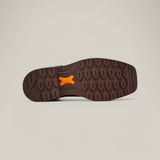 The image highlights a shoe sole in brown and orange hues, resembling the style of the Activator H2o Drk Brow - Composite Toe - 10060894. Its tread features hexagonal patterns with a vivid orange center, set against a plain light beige background.