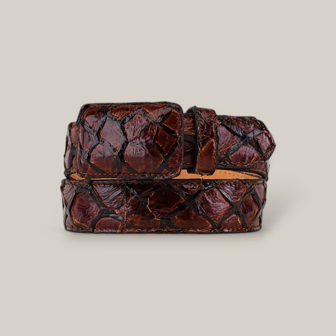 The Exotic Full Quilt Pirarucu Fish - Brown Belt features auténtica brown pirarucú leather with a textured, diamond-shaped pattern, showcased rolled up on a light gray background.