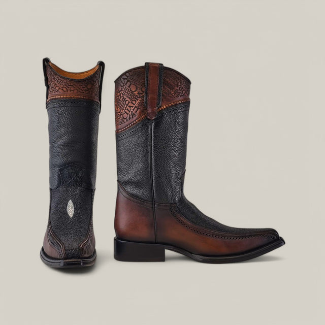 A pair of Black Stingray Laser boots, style CU628, features intricate laser-engraved shaft designs, black textured vamps, and brown leather soles. One boot is positioned forward while the other reveals a side view.