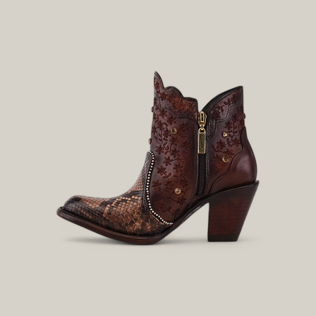 Meet the Ximena Bootie - Python Choco from the Platinum Collection: a stylish brown ankle boot featuring a round toe with Python Choco detailing, floral designs on the shaft, a side zipper, decorative studs, and a chunky heel.