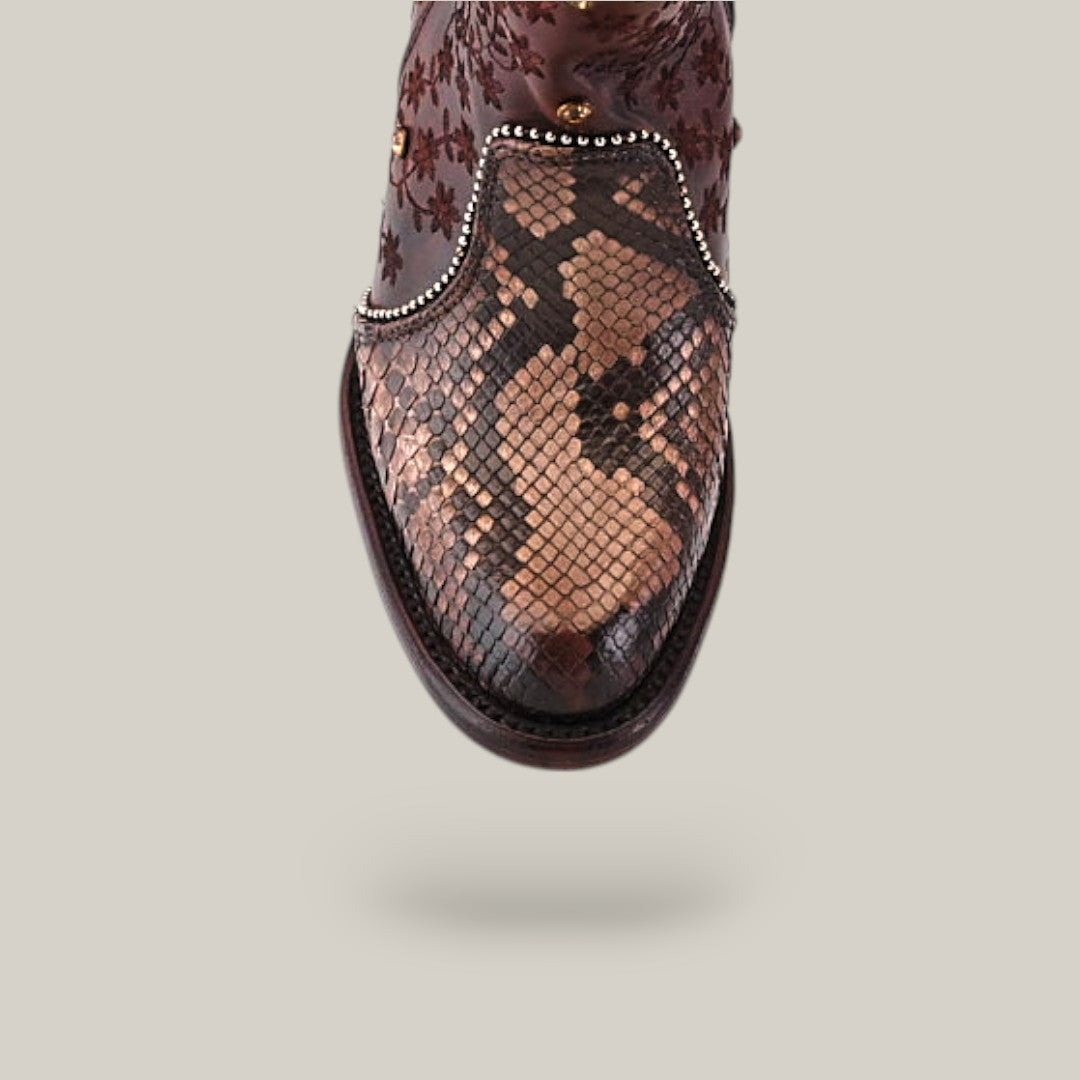 The Ximena Bootie from the Platinum Collection features a brown leather design, Python Choco-patterned round toe, ornate upper detailing, and small studs along the vamps edge for an elegant yet bold style.