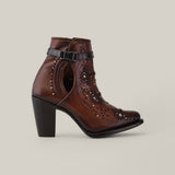 The Honey Embroidery & Studs & Harness - Round Toe - CU637 is a brown leather ankle boot with high heels, cut-out floral patterns, an ankle harness strap with a buckle, and metal studs. It features a plain beige background.