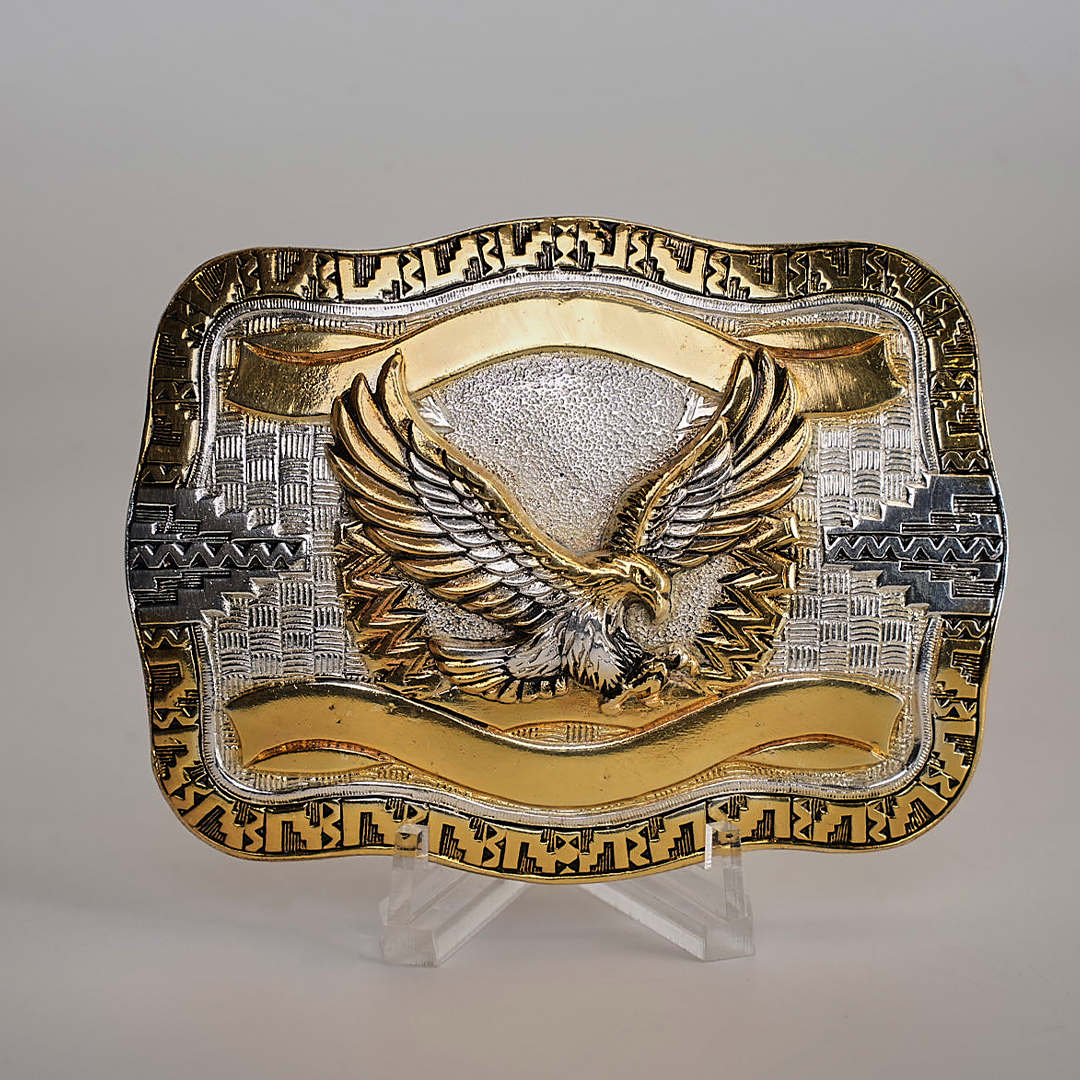 The Eagle Western Buckle features a stunning gold and silver palette with a majestic gold eagle at its center, wings spread wide. Its intricate border showcases classic western designs crafted in gleaming alpaca silver.