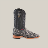 The Exotic Piraruco Fish - Rustic Bone - Square Toe cowboy boot showcases a textured, dark upper with intricate stitching. Its foot is covered in a scaly light-shaded Piraruco fish leather, complemented by a square toe and wooden heel, standing against a plain beige backdrop to exude rustic charm.