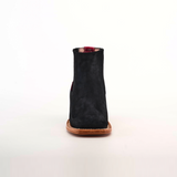 The Prime Suede Black Square Toe, a black suede ankle boot with a cowboy flair featuring a square toe and brown leather sole, is photographed from the front against a plain white background.