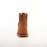 The Prime Suede Caramel Square Toe is a brown suede ankle boot with a square toe and leather sole, centered on a plain white background. Its red pull tab subtly peeks out at the top, adding a splash of color to its classic design.