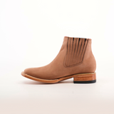 The Prime Suede Sand Square Toe is a tan leather ankle boot with side elastic panels for easy slip-on and a wooden stacked heel. Its sleek design, perfect for a fashion-forward wardrobe, is showcased on a plain white background to emphasize its elegance.