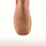 The Prime Suede Sand Square Toe is a tan leather cowboy boot with detailed stitching and a square toe, viewed from the top against a light background. This fashion-forward piece adds a rugged charm to any wardrobe.