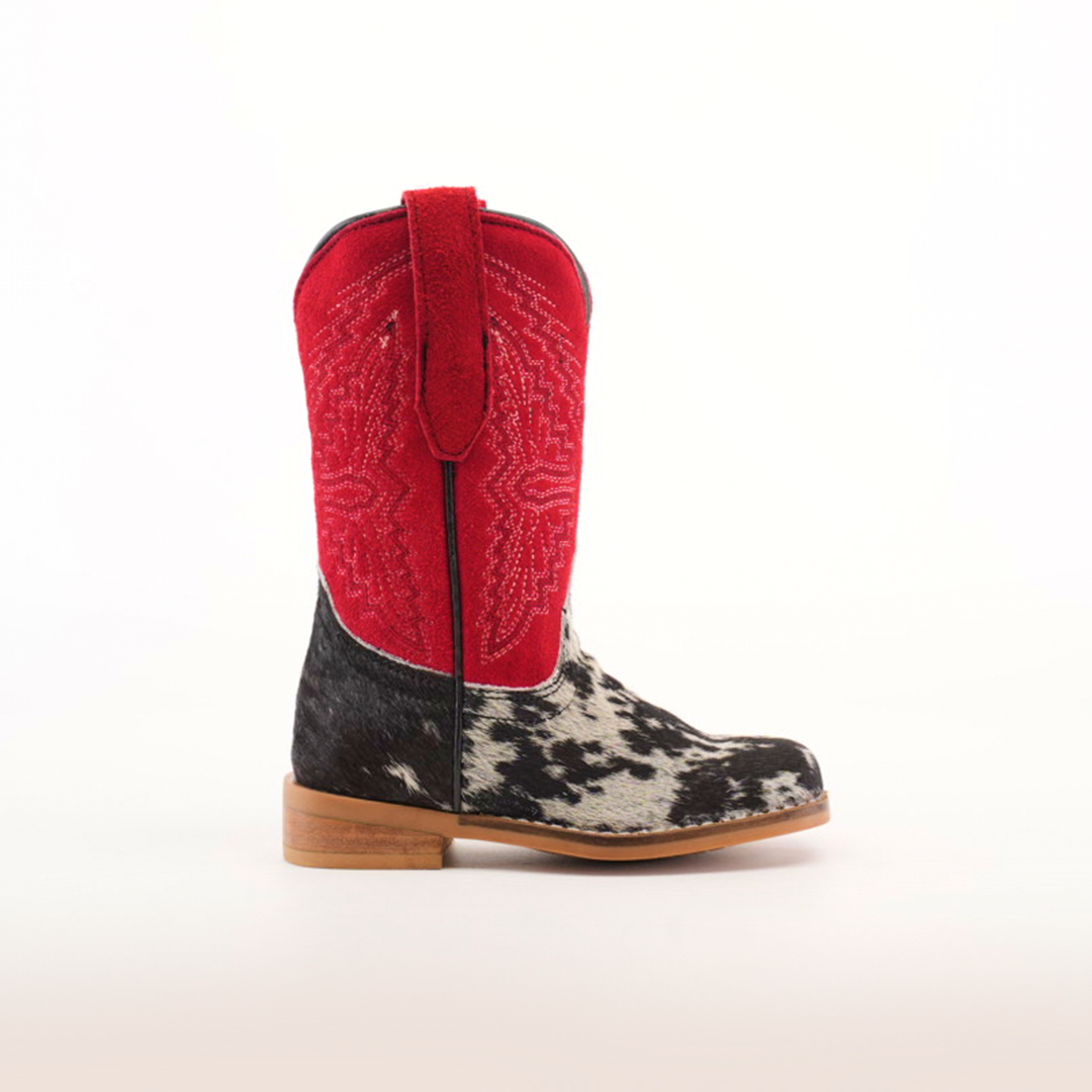 The Cowhide Hair Pinto Square Toe boot boasts a red upper with intricate stitching and a black and white cowhide pattern on the lower section. It features a square toe design resting on a sturdy brown sole, displayed against a plain white background.