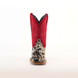 The Cowhide Hair Pinto Square Toe cowboy boot features a vibrant red shaft with detailed embroidery. Its foot showcases a unique black-and-white speckled cowhide design, resting on a light brown sole, embodying true western style, all displayed on a white background.