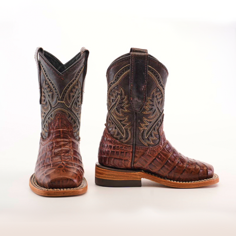 These handcrafted chocolate square toe cowboy boots feature a detailed caiman belly print on the toe and shaft. The left boot faces forward, while the right is in side profile, highlighting the intricate stitching on premium leather.