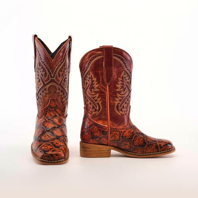 The Pirarucu Bass Print Cognac Square Toe cowboy boots feature intricate bass print patterns and a textured surface. Crafted from premium rich reddish-brown leather with a square toe and wooden heel, they stand stylishly against a plain white background.