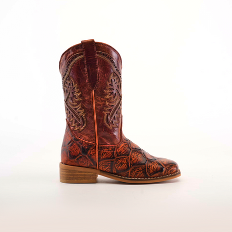 A single Pirarucu Bass Print Cogñac Square Toe cowboy boot made of premium brown leather features intricate shaft patterns and bass print texture on the lower part. Positioned on a plain light background with a low wooden heel and square toe, it faces left.