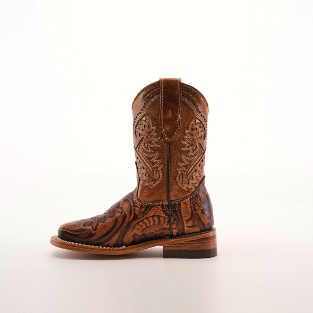 The Handtooled Leave Orix Square Toe is a single brown cowboy boot, adorned with intricate embroidery and floral patterns. Crafted from cowhide leather with a wooden heel, it stands upright on a plain white background, showcasing traditional craftsmanship and classic Western style.