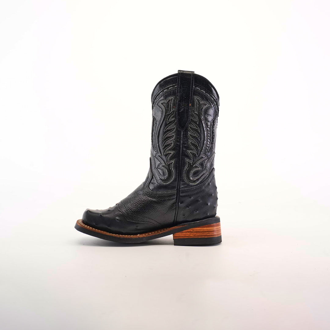 The Karoo Ostrich Half Cowhide Print Black Rodeo Toe boot boasts intricate stitching, a textured ostrich pattern, and a classic western vibe with its wooden heel, shown in side view on a white background.