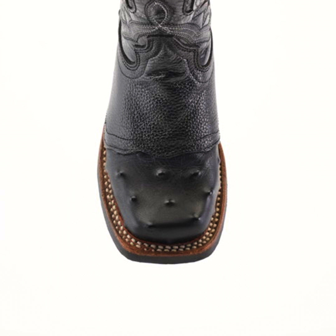 A detailed view of the Karoo Ostrich Half Cowhide Print Black Rodeo Toe boot highlights its western style, showcasing decorative stitching and textured ostrich leather. A brown sole with visible stitching complements the square toe, all set against a plain white backdrop for an elegantly rugged look.