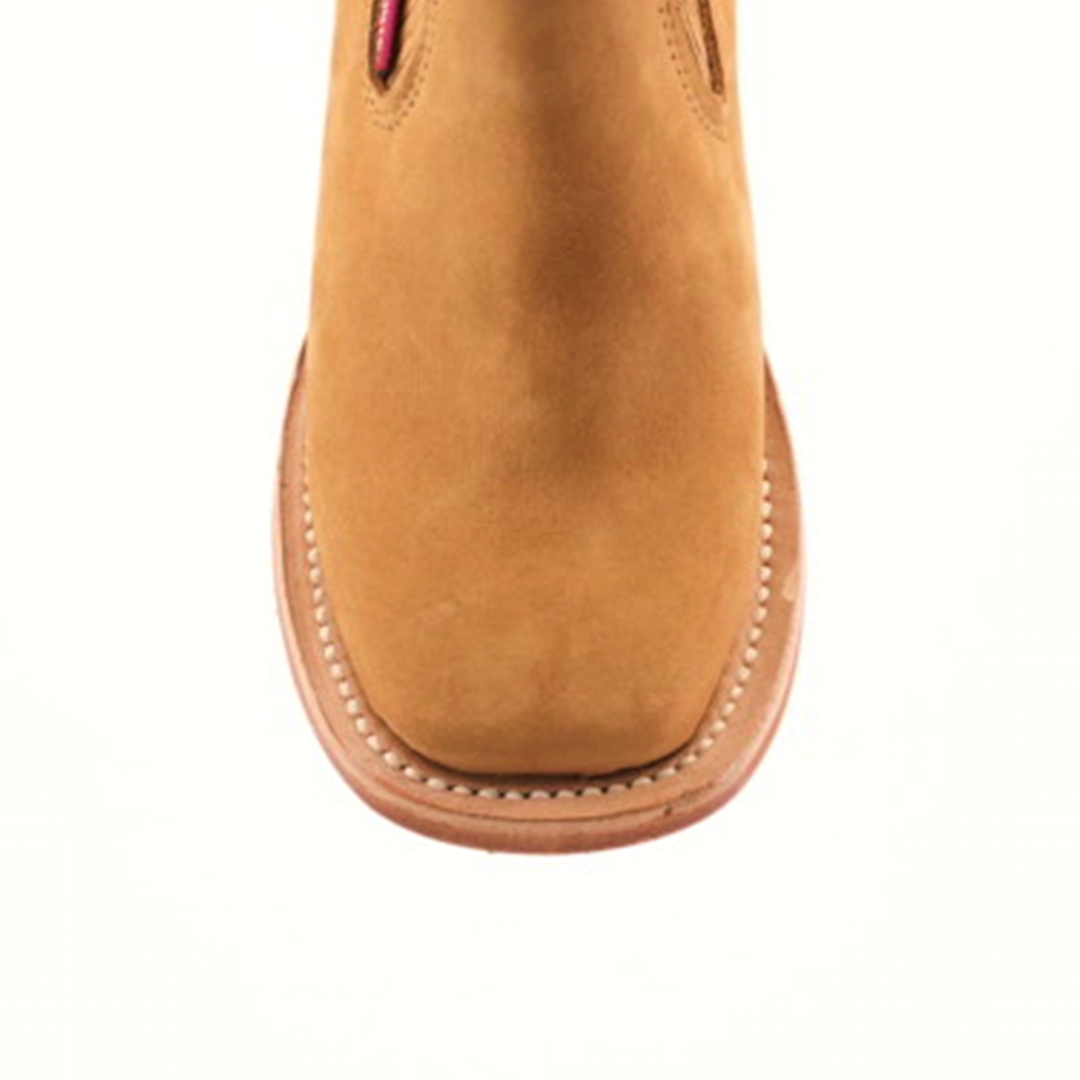 The Prime Suede Honey Square Toe is a tan suede ankle boot viewed from above, highlighting its stylish square toe and part of the upper. It features detailed stitching along the sole edge and boasts a smooth suede texture.