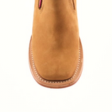 The Prime Suede Honey Square Toe is a tan suede ankle boot viewed from above, highlighting its stylish square toe and part of the upper. It features detailed stitching along the sole edge and boasts a smooth suede texture.