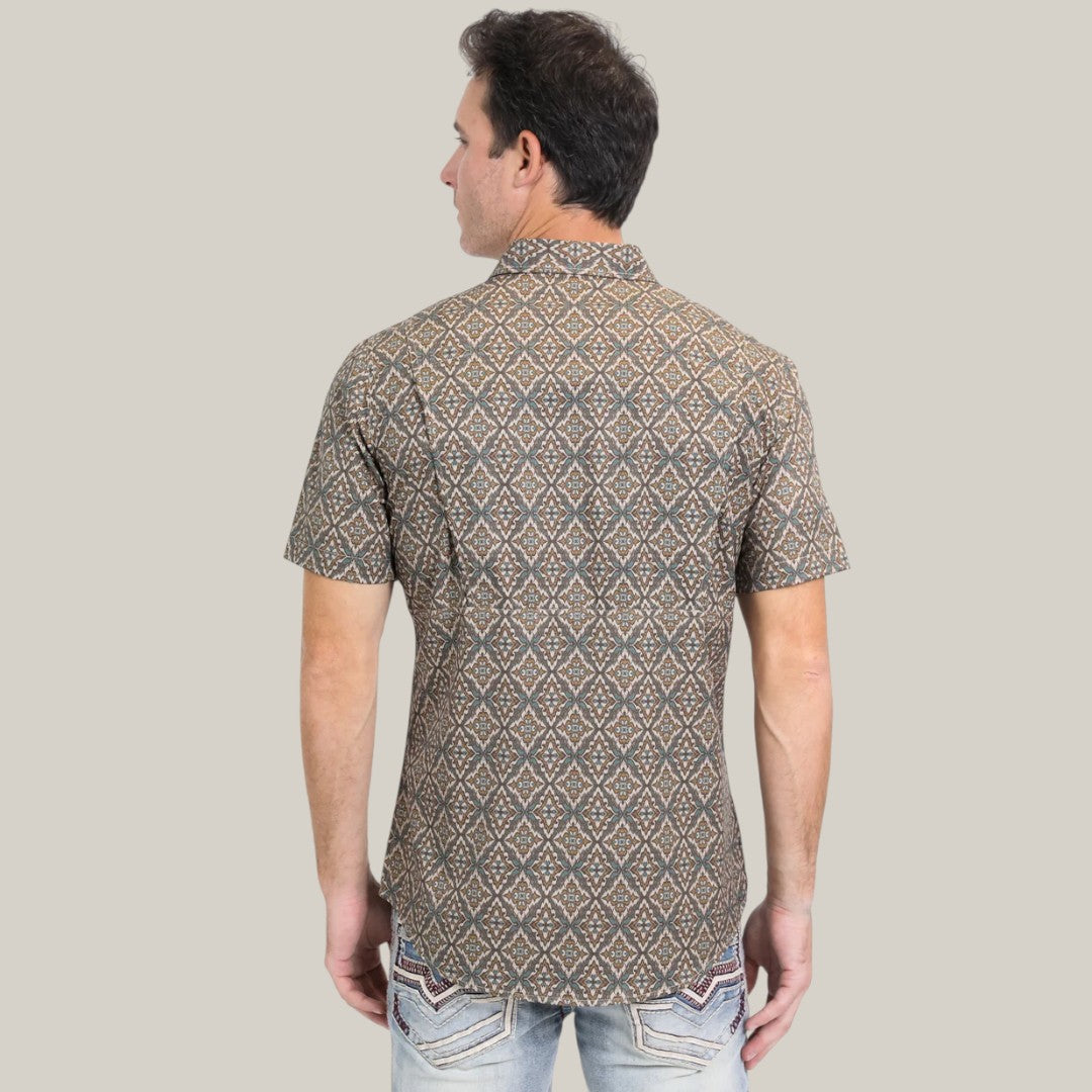 A person with short dark hair, facing away, wears the Mens Performance Western Short Sleeve Aztec Print Brown Shirt - PGW10638 and light blue jeans with decorative stitching against a simple light gray backdrop.