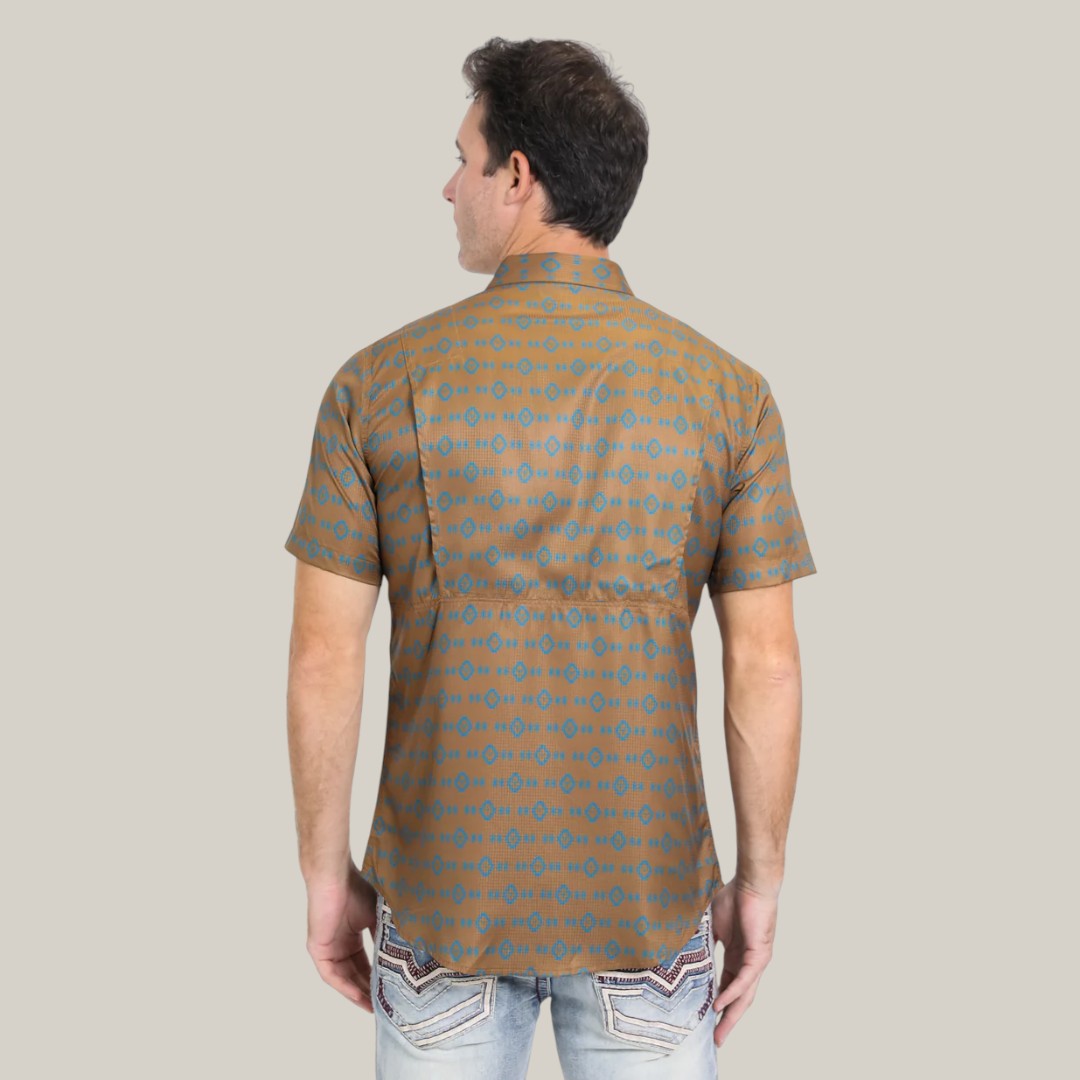 A man wearing the Mens Performance Western Short Sleeve Aztec Print Camel Shirt (PGW10613) and light blue jeans with back pocket stitching stands with his back to the camera on a plain light background. The shirt is crafted from lightweight, breathable fabric that pairs perfectly with the jeans.