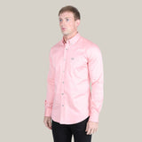 A person wears the Men’s Single Pocket Logo Modern Fit Stretch Dress Shirt in pink (CTL9826) with black pants, standing against a gray backdrop and glancing to the side.