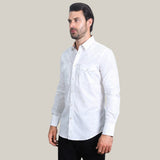 A man with dark hair and a beard wears the WPL10484, a modern fit mens white cotton/spandex long sleeve shirt featuring stylish snaps, with black pants. He stands against a light gray background, looking to the side with a neutral expression.