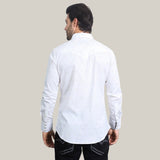 The dark-haired man, facing away, is wearing a Mens Western Modern Fit Long Sleeve White Shirt (WPL10484) made of premium cotton/spandex. It features stylish snaps that contrast with the plain light gray background and pairs effortlessly with dark jeans for a sleek look.