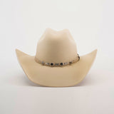 The 6X Chihuahua Bone, a light beige Western hat made from premium sheep wool, boasts a wide brim and a decorated band with metallic accents around the crown, standing out stylishly against a plain white background.