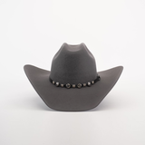 The 6X Bull Oxford is a gray felt cowboy hat with a wide brim, adorned with a decorative black band and circular silver embellishments around the crown, exemplifying luxury western wear against a plain white background.