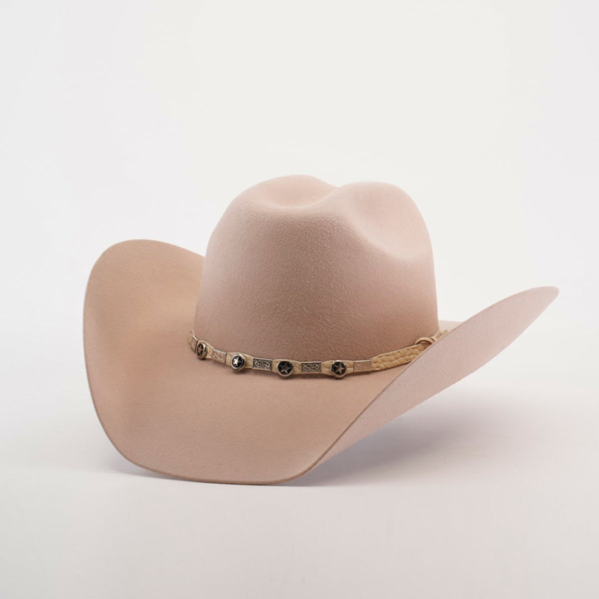 The 6X Bull Belly, a beige western hat with a wide brim and a decorative band with metallic embellishments, stands against a plain white background, epitomizing luxury western wear.