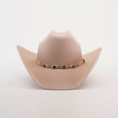 The 6X Bull Belly is a luxury western wear accessory featuring a light beige cowboy hat with a wide brim and adorned with round metal accents on the decorative band around the crowns base, all set against a plain white background.