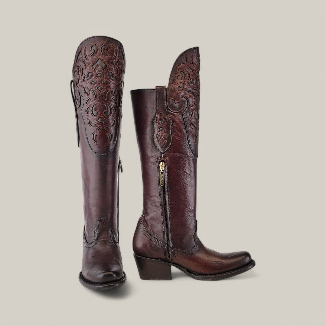 The California Tall Shaft Brown - Round Toe cowboy boots from the Platinum Collection feature ornate embossed patterns on dark brown leather, with side zippers and medium heels. The left boot stands upright while the right is slightly tilted, set against a light gray background.