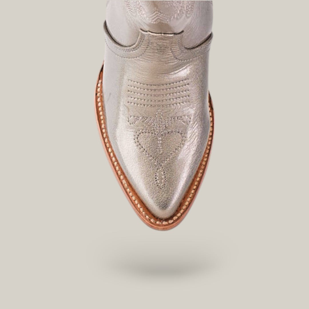 A close-up of a single cowboy boot from the Platinum Collection features the Linda Tall Shaft Mercury with J Toe. It showcases metallic sheen, intricate stitching, and detailed embroidery on a light background, focusing on the toe area.