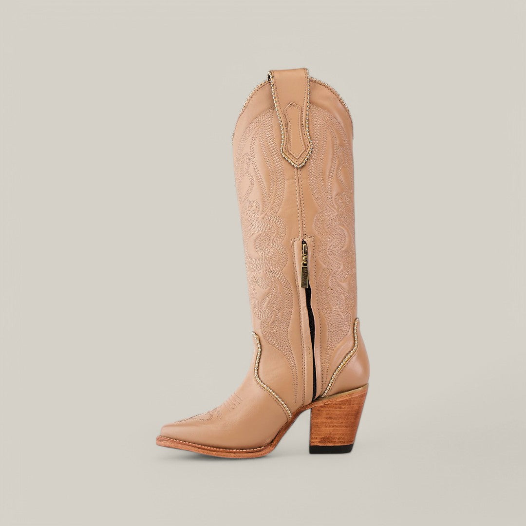 Introducing the Linda Studs Tall Shaft Cream - J Toe: a light tan leather cowboy boot with intricate embroidery, a stacked wooden heel, and a pointed toe. It features studs on the shaft, a side zipper for convenience, and a pull tab at the top.