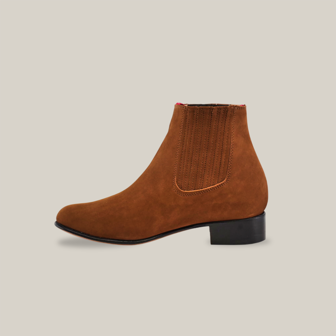 The Prime Suede Caramel Round Toe, a brown suede ankle boot with an elastic side panel and low black heel, epitomizes the charm of handcrafted footwear against a plain white background.