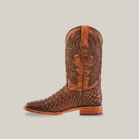 The Jumbo Python Print Rustic Brown boot showcases intricate shaft stitching and a textured foot design. This stylish square toe boot with a low wooden heel is elegantly photographed against a white background, facing left.