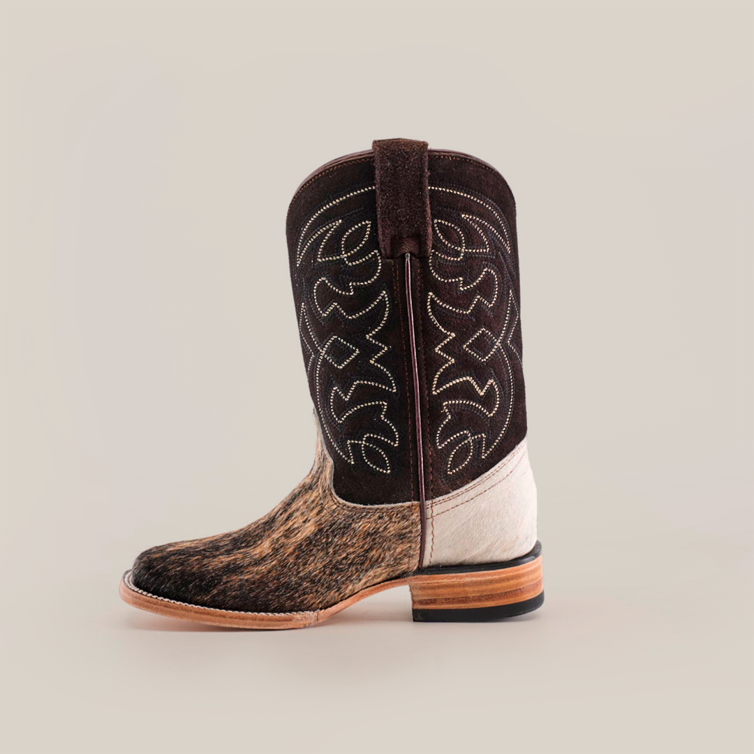 The Cowhide Hair Fawn Square Toe cowboy boot features a dark brown shaft with white stitching, a textured cowhide hair pattern on the lighter brown fawn-finished foot, and a square toe. It has a wooden sole with a low heel, all showcased against a plain white background.