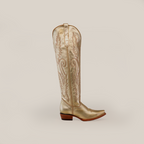The Brittany Gold - Tall Shaft - Snip Toe womens boot is a metallic gold handcrafted masterpiece featuring intricate stitching and a low wooden heel. Set against a plain gray background, its pointed toe and embroidered shaft pattern make it a standout piece.
