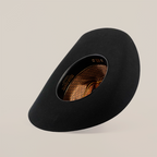 The 6X Doble SS Black showcases a wide-brimmed design, tilted to reveal an intricate interior with golden patterns. Set against a plain white background, it highlights the hats elegant shape and texture, echoing the timeless charm of Western headwear.