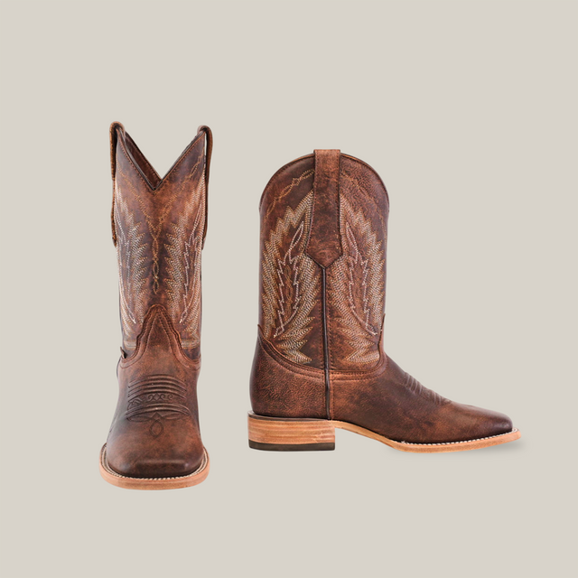 A pair of Bombay Camel - Square Toe cowboy boots in brown premium cowhide leather, featuring intricate decorative stitching, is displayed against a plain white background with one boot facing forward and the other angled sideways.